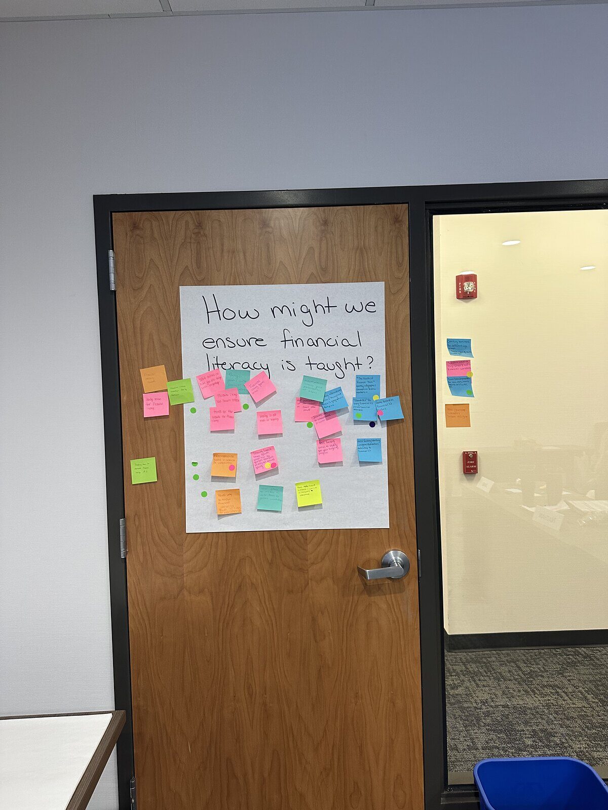 A chart reading How might we ensure financial literacy is taught, surrounded by sticky notes