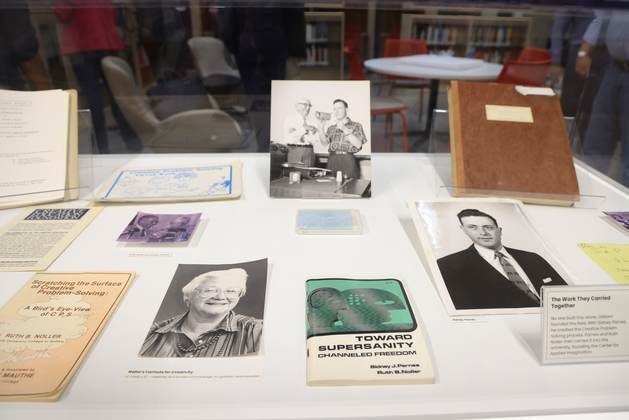 Archival books, portraits and documents arranged in a display case